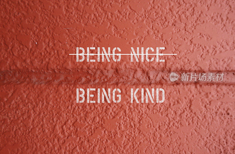 橙色墙壁上的文字BEING NICE(横线)BEING Kind -停止做好事的概念(一种试图在社交行为中看起来很好的行为)，而是做更多的好事来帮助或鼓舞他人